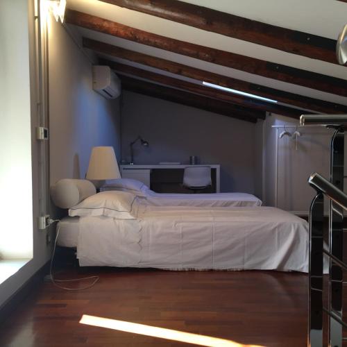 a bedroom with a white bed and a wooden floor at Elegante affascinante Appartamento in centro storico in Caorle