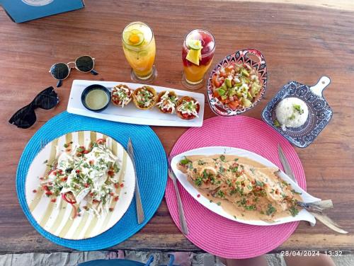 a wooden table with plates of food and drinks at Palenque Beach House in San Onofre