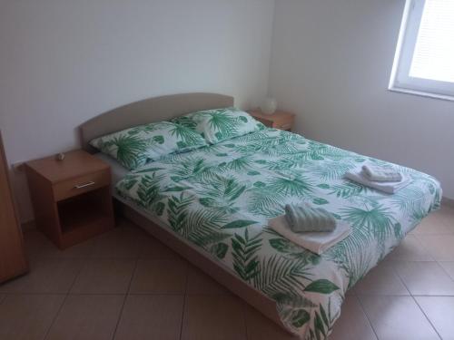 a bedroom with a bed with a green leafy bedspread at Apartmani Marko & Joso in Biograd na Moru