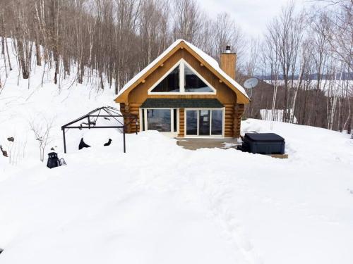 a log cabin in the snow with a sign in front at Le Petit Domaine Caché - Lac-Simon in Lac-Simon