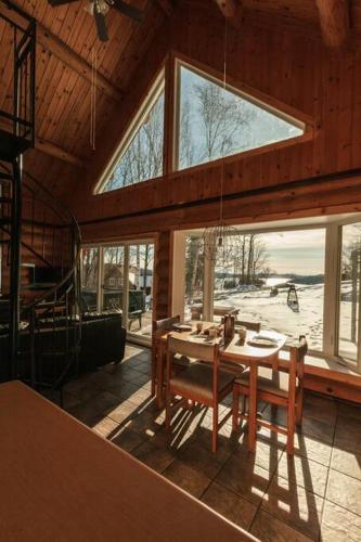a dining room with a table and some windows at Le Petit Domaine Caché - Lac-Simon in Lac-Simon