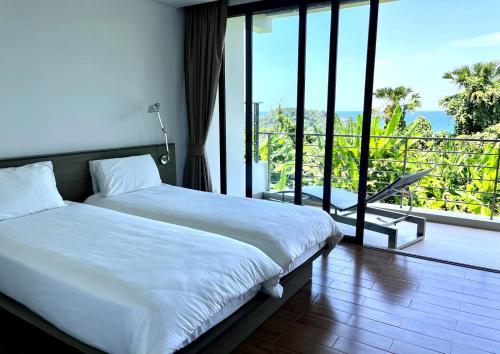 a bedroom with a bed and a balcony with a view at 07 - Luxurious Haven with Mesmerizing Views in Surin Beach
