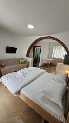 a large white bed in a room with a couch at Aliaj's Guest House in Berat