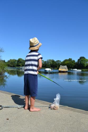 a young boy is holding a fish with a fishing pole at Mobil home Gîte Canal Nantes à Brest 40 minutes Nantes et Saint-Nazaire in Guenrouet