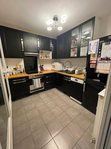 Il comprend une cuisine avec des placards noirs et du carrelage. dans l'établissement appartement 6 pers à 1km du village olympique, à Saint-Ouen