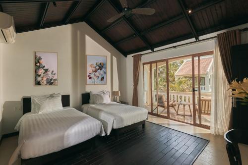 En Retreat Villa Hoi An في Hiếu Nhơn: غرفة نوم بسريرين وشرفة