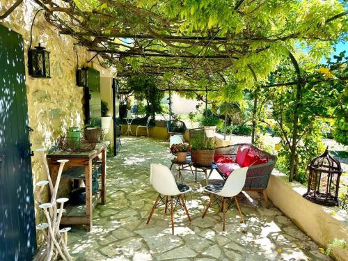 un patio avec une table et des chaises sous une pergola dans l'établissement Charmant mas provençal au coeur des vignes, au Castellet