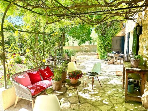 une terrasse avec un canapé et des chaises sous une pergola dans l'établissement Charmant mas provençal au coeur des vignes, au Castellet