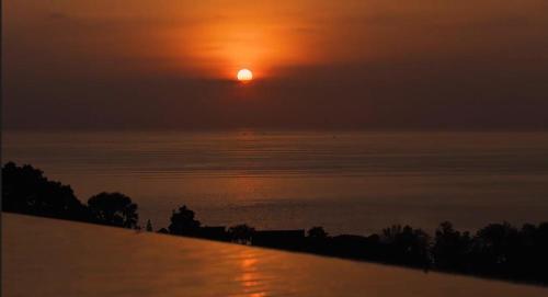 a sunset over the water with the sun in the sky at 07 - Luxurious Haven with Mesmerizing Views in Surin Beach