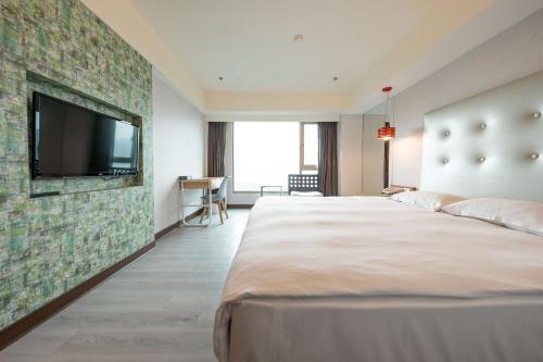 a bedroom with a large bed and a flat screen tv at 觀海樓海景大飯店 Hotel Cloud Riverside in Tamsui
