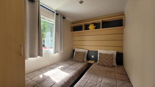 two beds in a small room with a window at MobilHome Nicolette EUROPAPARK 20min in Boofzheim