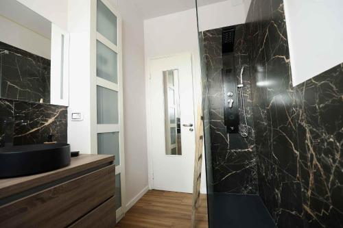 uma casa de banho com um chuveiro e uma parede em mármore preto em SWEET HOME FIERA em Bolonha