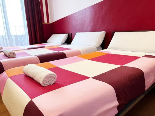 a row of beds in a room with colorful blankets at Hostal La Casa de La Plaza in Madrid