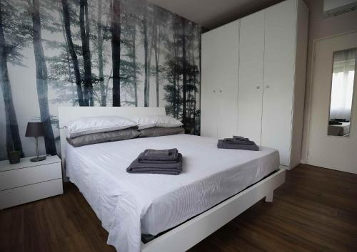 um quarto com uma cama branca com árvores na parede em SWEET HOME FIERA em Bolonha