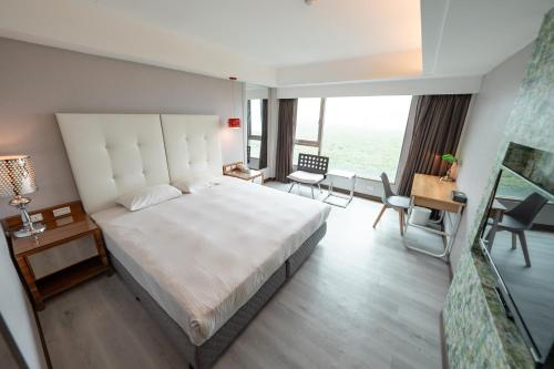 a bedroom with a large white bed and a desk at 觀海樓海景大飯店 Hotel Cloud Riverside in Tamsui