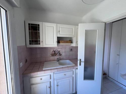 une cuisine avec des armoires blanches et un évier dans l'établissement St Raphaël tout à pieds, à Saint-Raphaël