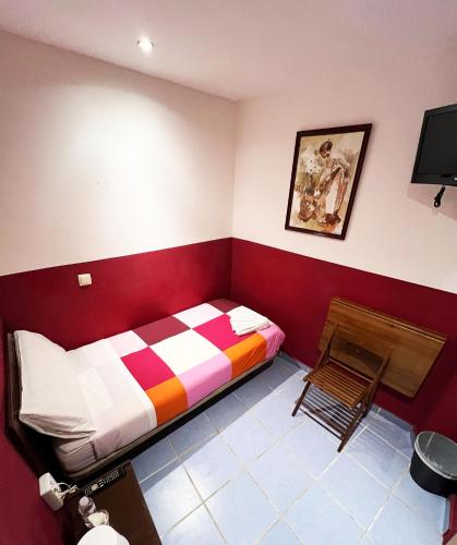 a bedroom with a colorful bed and a chair at Hostal La Casa de La Plaza in Madrid