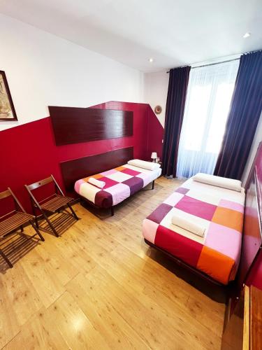 a bedroom with two beds and a red wall at Hostal La Casa de La Plaza in Madrid