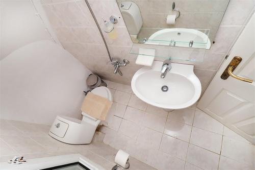 a bathroom with a sink and a toilet and a mirror at Victoria House Pefkohori 3 bedrooms 12 guests in Pefkohori