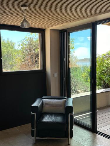 a room with a chair in front of a window at Villa Libecciu in Sainte-Lucie de Porto-Vecchio