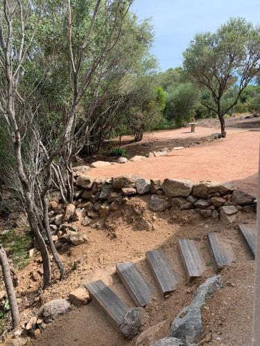 a bench sitting in the dirt next to a stone wall at Villa Libecciu in Sainte-Lucie de Porto-Vecchio