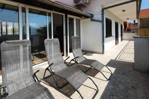 three chairs sitting on a patio in front of a house at Apartment GIDAS in Zadar