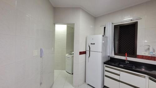 uma cozinha branca com um frigorífico e um lavatório em Apartamento no Guarujá - Enseada no Guarujá