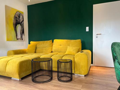 un sofá amarillo en una sala de estar con 2 mesas en Gemütliches 3 Zimmer Apartment nahe Science Park en Blaustein