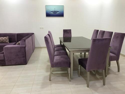 a dining room with purple chairs and a table and a couch at شاليهات رانديفو العاب مائية مع مسبح in Riyadh