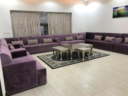 a living room with a purple couch and tables at شاليهات رانديفو العاب مائية مع مسبح in Riyadh