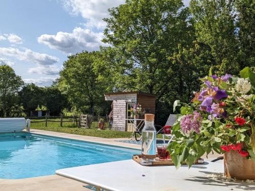 - une table avec des fleurs à côté de la piscine dans l'établissement Domaine Dauget, à Saint-Maurice-la-Clouère
