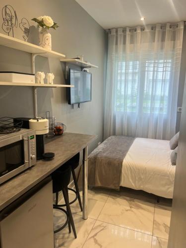 - une cuisine avec un lit et un bureau avec un four micro-ondes dans l'établissement Charming Studio 16, à Paris