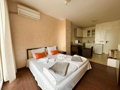 1 dormitorio con 1 cama blanca grande con almohadas de color naranja en North Beach Apartments, en Primorsko