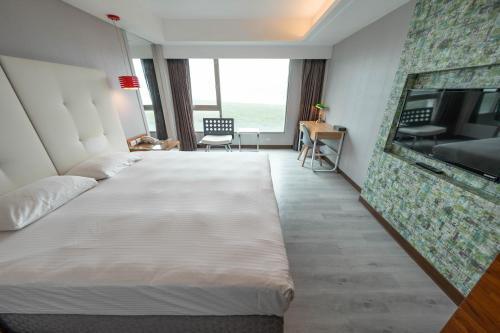a hotel room with a large bed and a flat screen tv at 觀海樓海景大飯店 Hotel Cloud Riverside in Tamsui