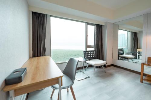 a room with a desk and chairs and a large window at 觀海樓海景大飯店 Hotel Cloud Riverside in Tamsui