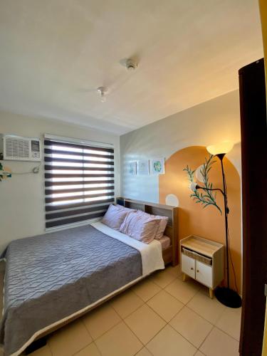 1 dormitorio con cama, lámpara y ventana en Minimalist Condo One Spatial Iloilo 2 Bedroom Unit en Iloílo