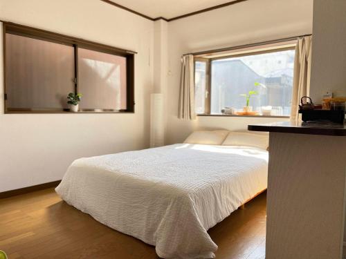 a white bedroom with a bed and a window at 眠りの癒201 I Cozy Apt, 3min Beach, Bus, Train, Onsen, Izakaya, WiFi in Beppu