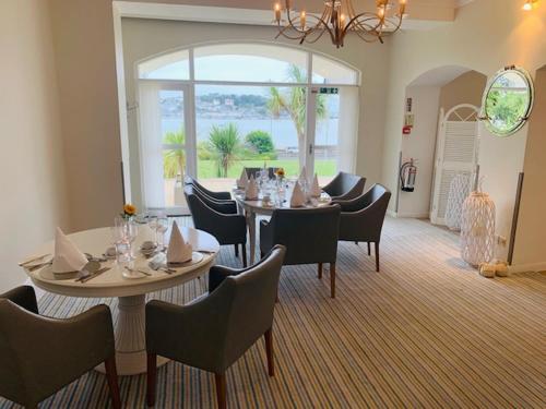 a dining room with tables and chairs and a large window at The Commodore Hotel in Instow