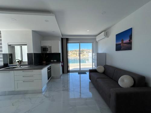 uma ampla sala de estar com um sofá e uma cozinha em Seaview Setters Penthouse Marsaskala em Marsaskala