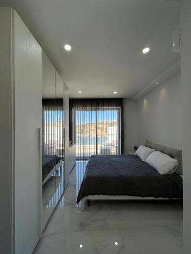 um quarto com uma cama e uma grande janela em Seaview Setters Penthouse Marsaskala em Marsaskala