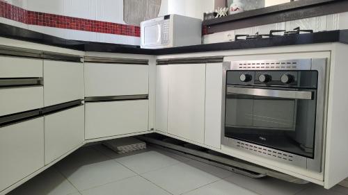 uma cozinha com armários brancos e um micro-ondas em Apartamento no Guarujá - Enseada no Guarujá