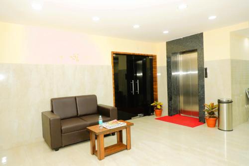 eine Lobby mit einem Stuhl, einem Tisch und einem Aufzug in der Unterkunft Hotel Shri Durga International in Bangalore