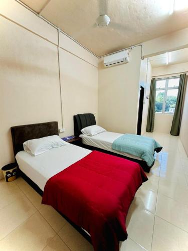 a bedroom with two beds and a red blanket at RS INN in Rantau Panjang