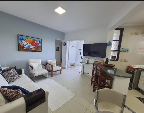 a living room with a couch and a table and a tv at Seu lar na praia das Toninhas em Ubatuba in Ubatuba