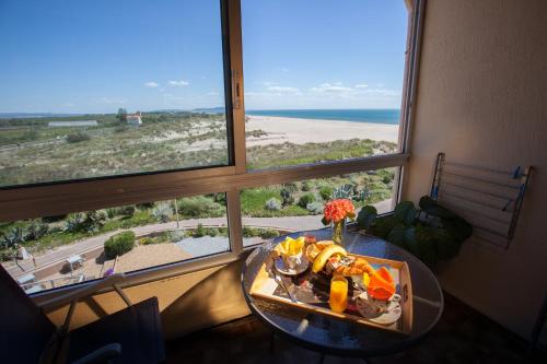 a table with a tray of food in front of a window at Hotel Les Dunes in Marseillan