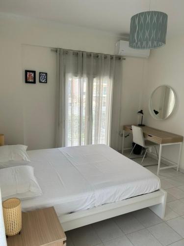 a white bedroom with a large bed and a desk at Mary Lo Guest House in Nydri