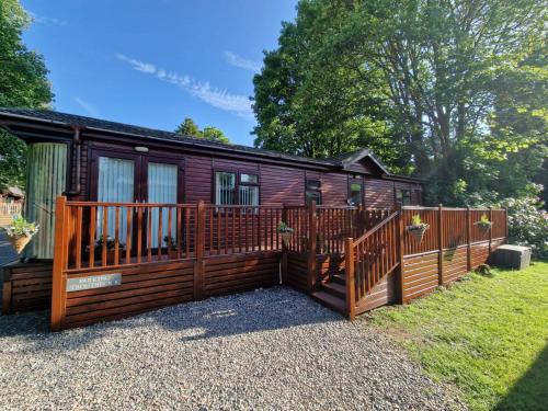a wooden cabin with a fence and a yard at Windermere lodge,sleeps 6 in Windermere