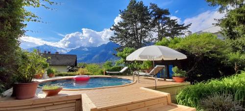 a swimming pool with an umbrella and a table and chairs at Home Suite Home Bed & Breakfast in Merano