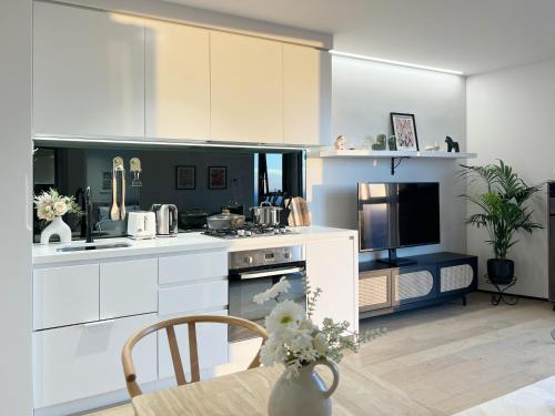 a kitchen with white appliances and a table with a vase of flowers at Sky View 1B1B APT in the CBD in Melbourne