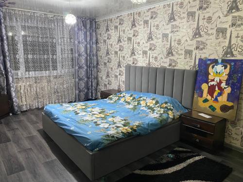 a bedroom with a bed with a blue comforter with animals on it at Однокомнатная квартира in Shymkent